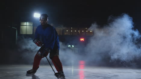 Professional-hockey-player-with-a-stick-accelerates-on-the-ice-and-stops-abruptly-in-front-of-the-camera-looking-straight-into-the-camera